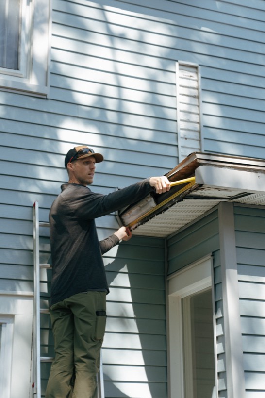 Dave Arthur measuring a soffit from a ladder